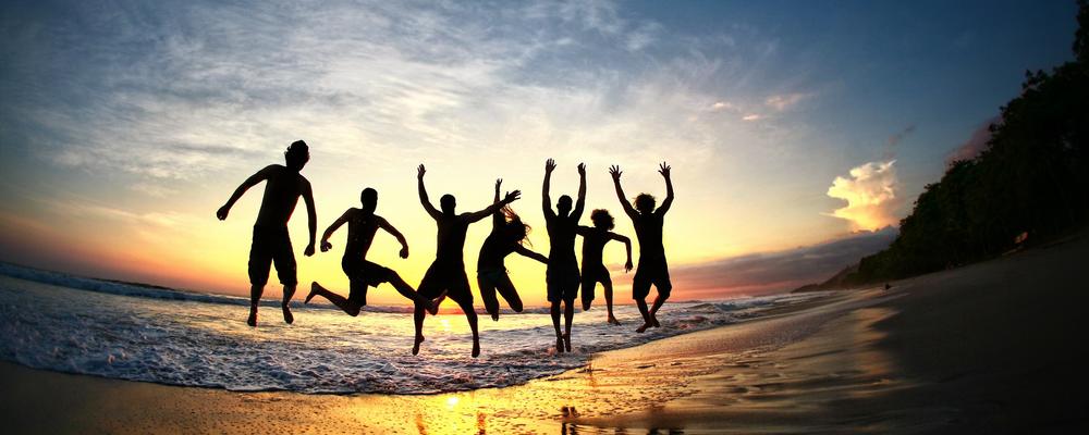 Människor hoppar i glädje på strand